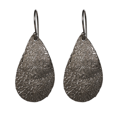 Queen Pear er et sæt flotte øreringe i sort sterlingsølv med flade vedhæng i let banket overflade, der giver øreringene en flot struktur og en rå kant. Øreringene er lette at bære og er perfekt til en aften i byen, eller hvis hverdags-outfittet skal pifte